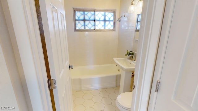 bathroom with tiled shower / bath combo, toilet, and tile patterned flooring