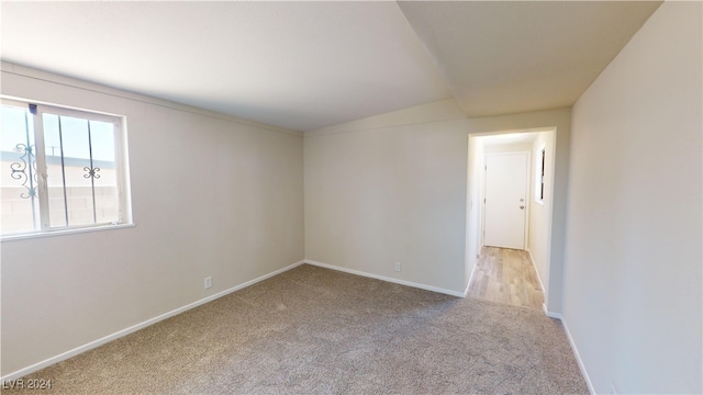 spare room featuring vaulted ceiling and light colored carpet