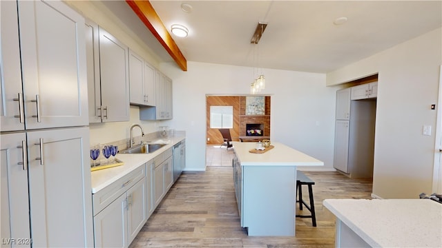 kitchen featuring light wood-type flooring, a kitchen island, sink, and a kitchen breakfast bar