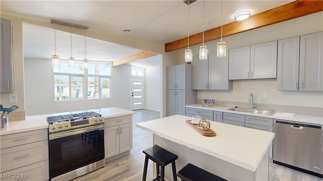 kitchen featuring hanging light fixtures, stainless steel appliances, sink, and light hardwood / wood-style floors