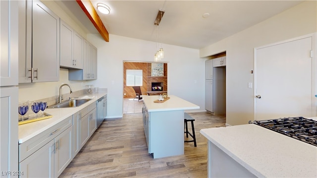 kitchen featuring pendant lighting, a kitchen breakfast bar, a center island, sink, and light hardwood / wood-style floors