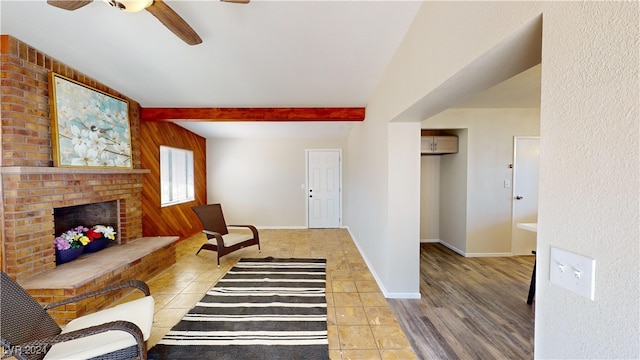 living room with light hardwood / wood-style floors, ceiling fan, beamed ceiling, and a fireplace