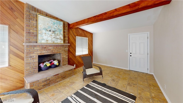 living room with a fireplace, beam ceiling, and wooden walls