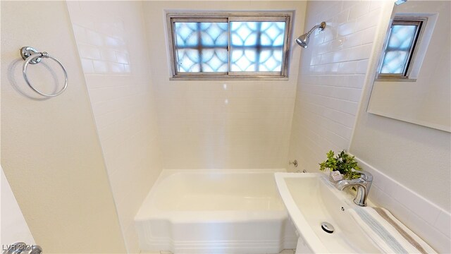 bathroom featuring a healthy amount of sunlight and tiled shower / bath