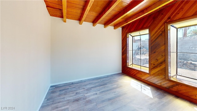 empty room with wood ceiling, hardwood / wood-style floors, wood walls, and beam ceiling