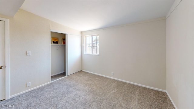 unfurnished bedroom featuring light carpet, vaulted ceiling, and a closet