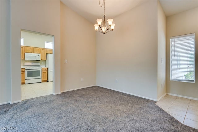 spare room with lofted ceiling, light colored carpet, and an inviting chandelier