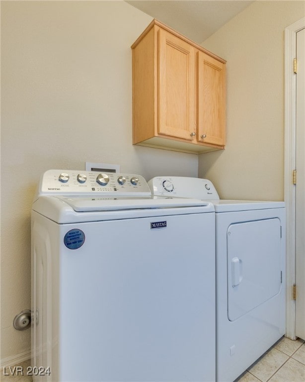 laundry area featuring washer and dryer, cabinets, and light tile patterned floors