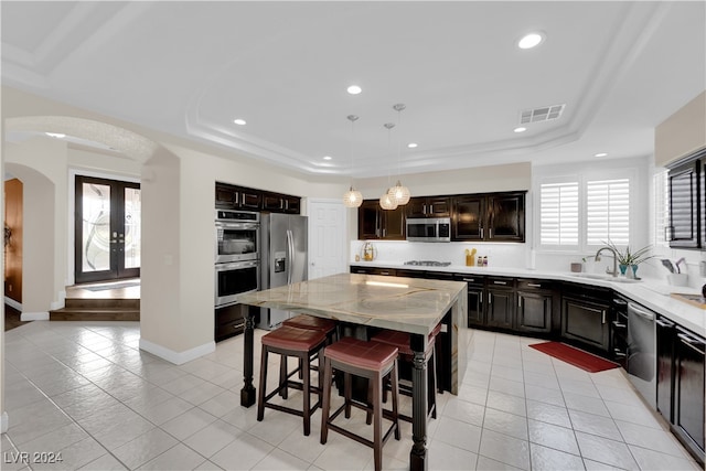 kitchen with appliances with stainless steel finishes, french doors, a kitchen island, and a wealth of natural light