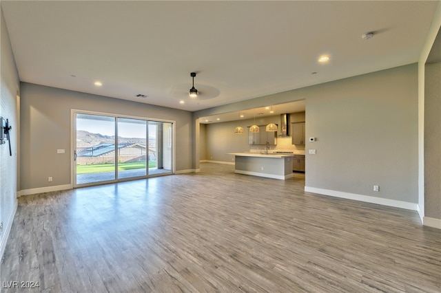 unfurnished living room featuring sink, hardwood / wood-style flooring, a mountain view, and ceiling fan