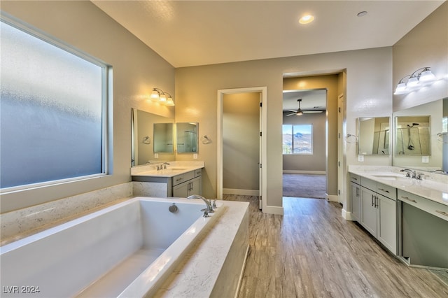 bathroom featuring tiled bath, hardwood / wood-style flooring, vanity, and ceiling fan