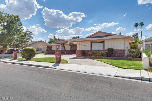 ranch-style home with brick siding, concrete driveway, a front yard, and fence