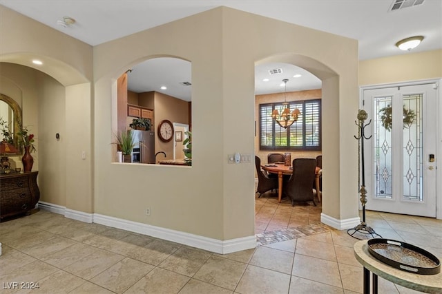 tiled foyer featuring an inviting chandelier and french doors