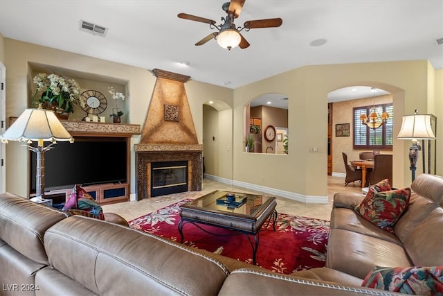 tiled living room featuring lofted ceiling, ceiling fan with notable chandelier, and a fireplace