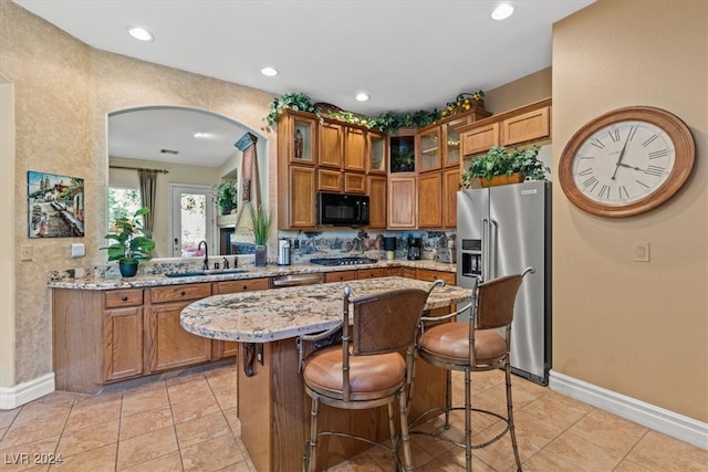 kitchen featuring high end refrigerator, kitchen peninsula, sink, and light stone counters