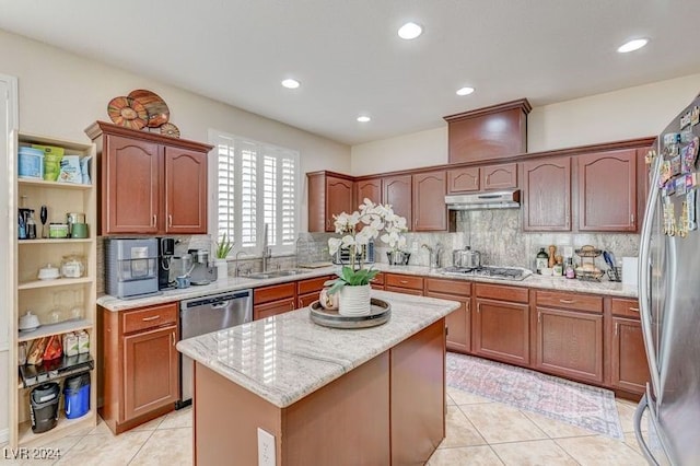 kitchen with light tile patterned floors, appliances with stainless steel finishes, light stone countertops, a kitchen island, and decorative backsplash