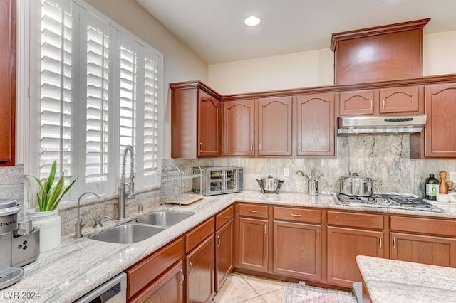 kitchen with stainless steel gas stovetop, backsplash, sink, and light tile patterned flooring