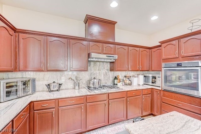 kitchen with stainless steel appliances, light stone countertops, and tasteful backsplash