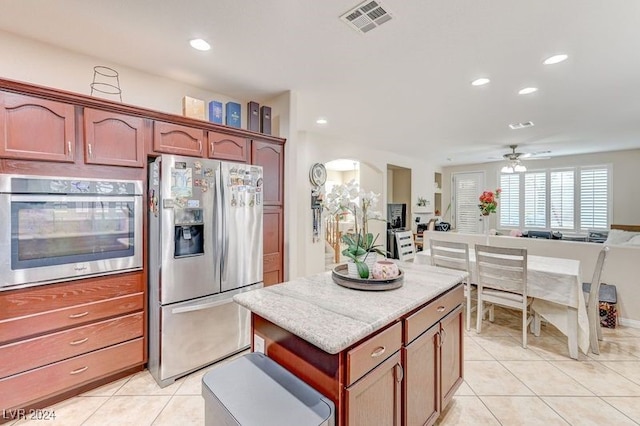 kitchen featuring ceiling fan, light tile patterned floors, appliances with stainless steel finishes, and light stone countertops