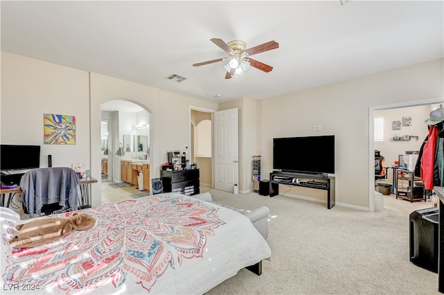 bedroom with light colored carpet, ceiling fan, and ensuite bathroom