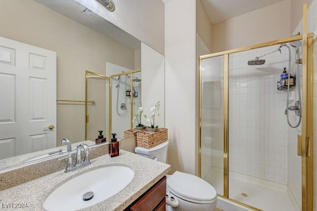 bathroom featuring a shower with shower door, toilet, and vanity