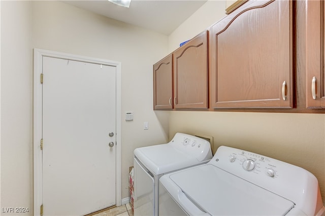 clothes washing area with washing machine and clothes dryer, cabinets, and light tile patterned floors