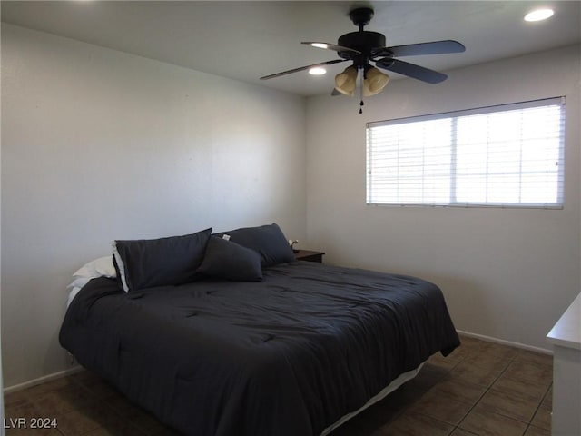 bedroom with dark tile patterned floors and ceiling fan