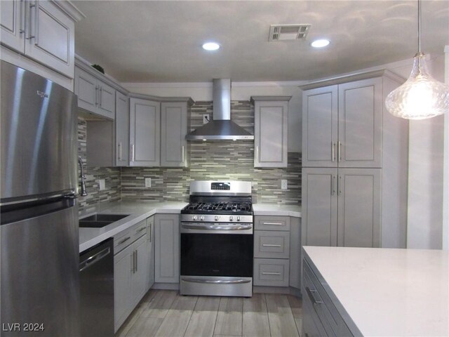 kitchen with gray cabinetry, backsplash, hanging light fixtures, wall chimney exhaust hood, and appliances with stainless steel finishes