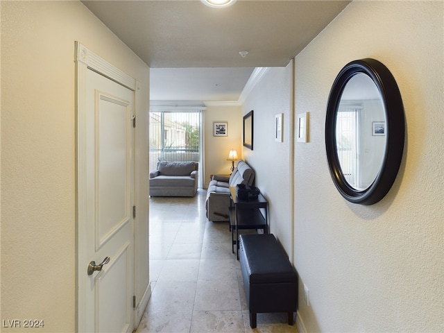 hall with ornamental molding and light tile patterned floors