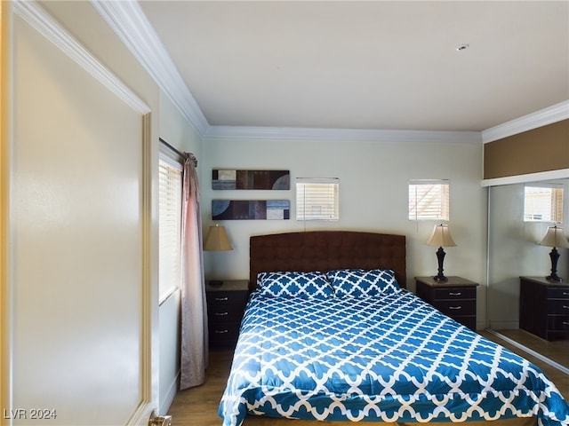 bedroom featuring multiple windows, hardwood / wood-style flooring, and ornamental molding