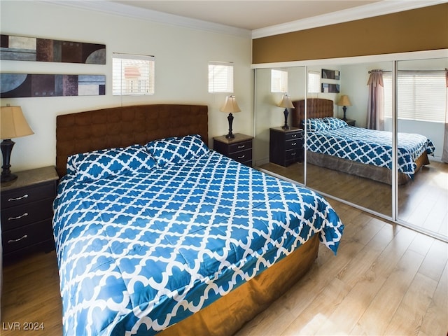 bedroom with crown molding, light hardwood / wood-style flooring, and a closet