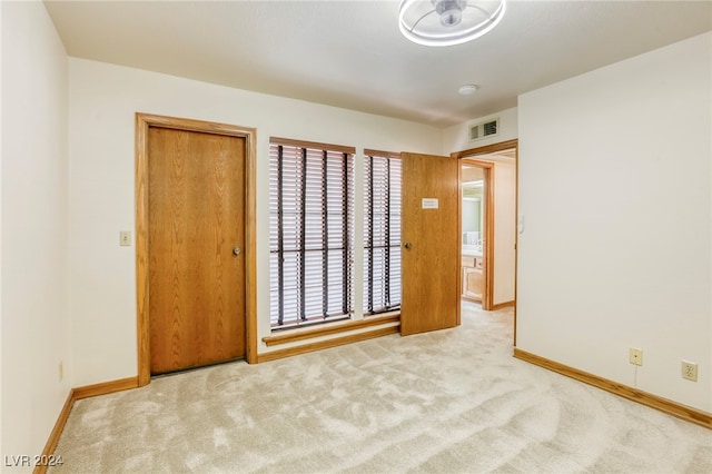 unfurnished bedroom featuring visible vents, light carpet, and baseboards