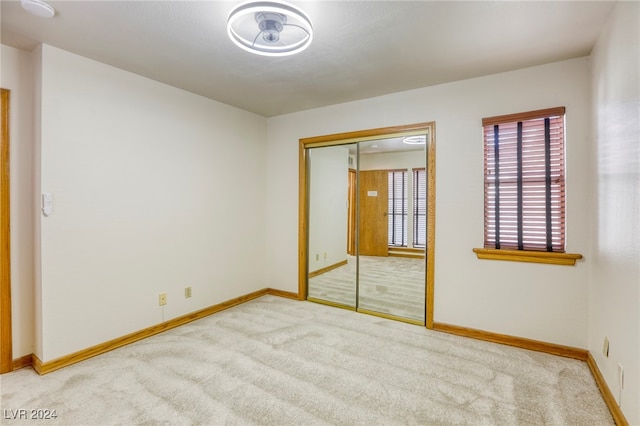 unfurnished bedroom featuring light carpet and a closet