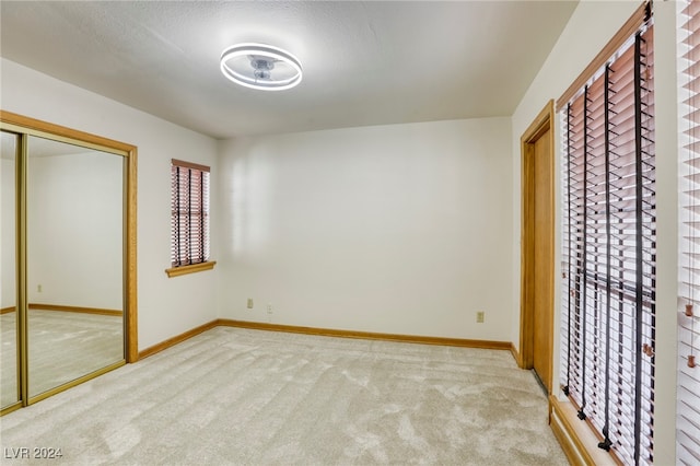 unfurnished bedroom with a textured ceiling, light carpet, and a closet