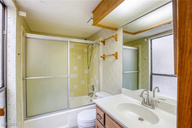 full bathroom with combined bath / shower with glass door, vanity, and toilet