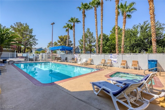 community pool featuring a community hot tub, a patio area, and fence