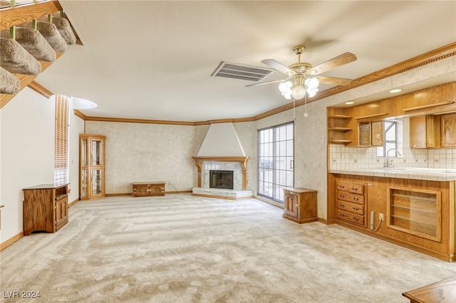 unfurnished living room featuring light carpet, ornamental molding, a fireplace, and visible vents