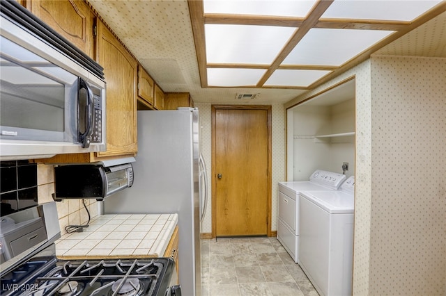 interior space featuring brown cabinets, tile countertops, visible vents, appliances with stainless steel finishes, and washer and dryer