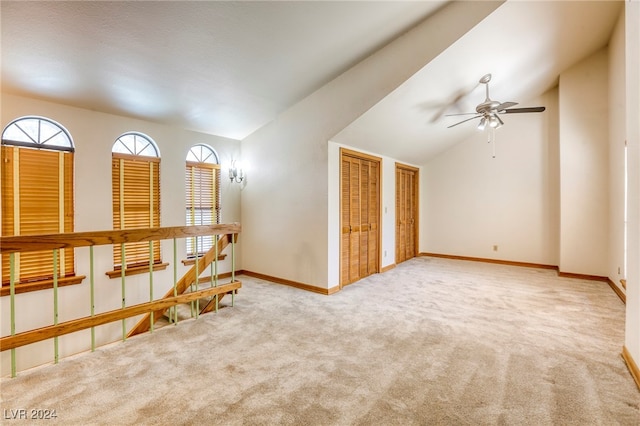 empty room featuring lofted ceiling, light carpet, and ceiling fan