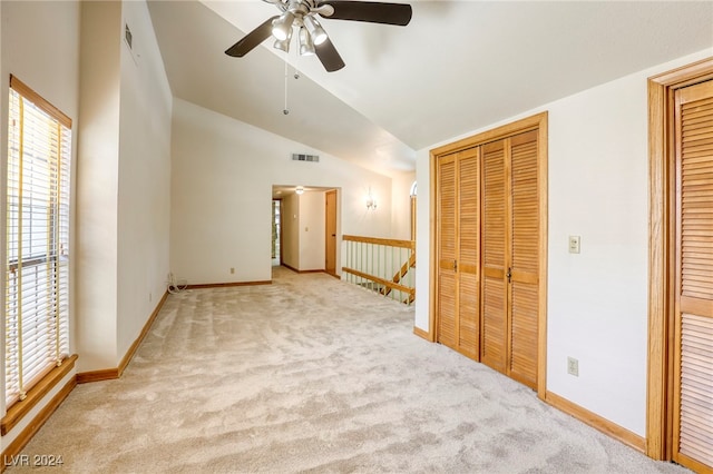 unfurnished bedroom with light carpet, baseboards, visible vents, lofted ceiling, and two closets