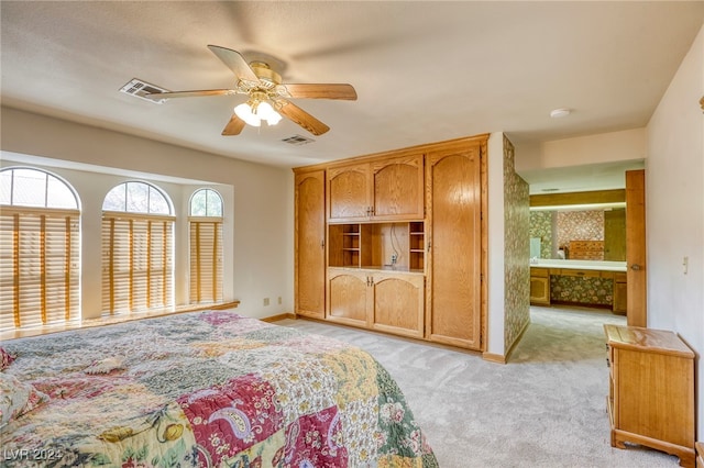 bedroom featuring connected bathroom, light carpet, and ceiling fan