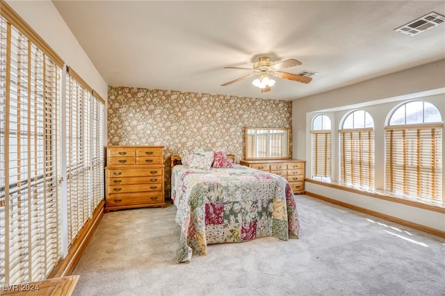 carpeted bedroom with visible vents, ceiling fan, baseboards, and wallpapered walls