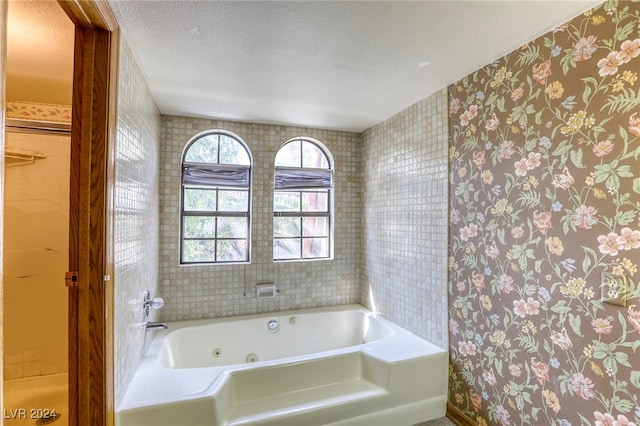 full bath featuring a textured ceiling and a tub with jets