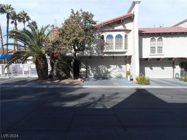 view of front of house with a garage, fence, a tile roof, concrete driveway, and stucco siding