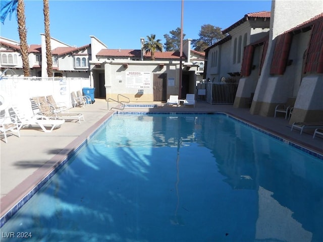 pool with a patio area and fence