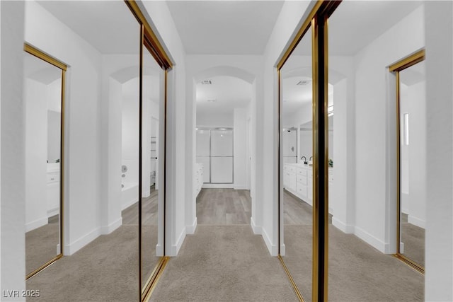 hall with light colored carpet and sink