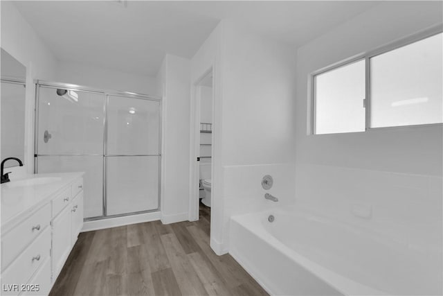 full bathroom featuring hardwood / wood-style flooring, vanity, toilet, and separate shower and tub