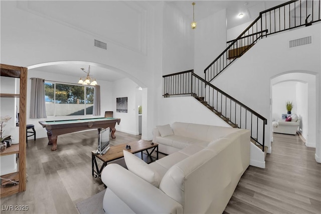 living room featuring a high ceiling, light wood-type flooring, and billiards