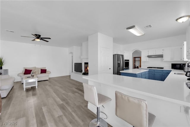 kitchen with black appliances, white cabinetry, a kitchen bar, a center island, and kitchen peninsula