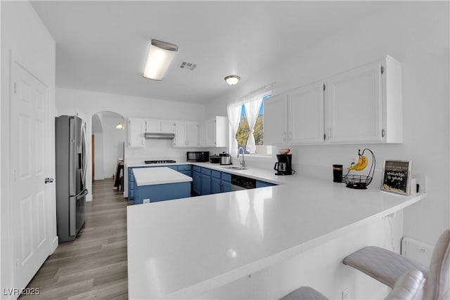 kitchen with sink, a breakfast bar, stainless steel appliances, white cabinets, and kitchen peninsula